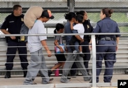 Ever Castillo, left, and his family, immigrants from Honduras, are escorted back across the border by U.S. Customs and Border Patrol agents, June 21, 2018, in Hildalgo, Texas.
