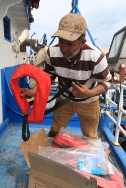 Tunisian fishermen prepare life jackets to be used in case they meet migrants in distress at sea, May 21, 2019, at the port of Zarzis, Tunisia. Most of the fishermen have already brought back migrants, saving hundreds of lives over the years.