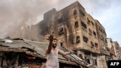 A man reacts outside a burning collapsed building following Israeli bombardment in Gaza City, Oct. 11, 2023.