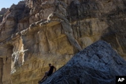 A man descends a rock on the bank of the Rio Grande, just a few feet from a cliff wall that is Mexico, in Santa Elena Canyon, at Big Bend National Park in Texas, March 27, 2017.