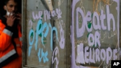 FILE - A worker stands by the abandoned warehouses that for months have been a make-shift shelter for migrants from the Middle East and Africa in Belgrade, Serbia, May 12, 2017.
