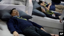 FILE - People try out smart beds during CES International, Saturday, Jan. 7, 2017, in Las Vegas. The bed has sensors that adjust the comfort and firmness depending on the user's position. It also warms the foot area prior to bedtime and it can sense snori