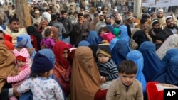 FILE - Afghan refugee families wait for their turn to be registered outside the government registration office in Peshawar, Pakistan, Feb. 8, 2017.