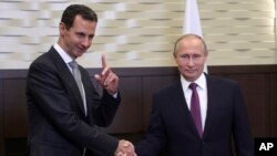FILE - Russian President Vladimir Putin (R) shakes hands with Syrian President Bashar Assad in the Black Sea resort of Sochi, Russia, Nov. 20, 2017.
