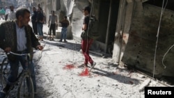 阿勒颇居民走过被政府军空袭后的现场和血迹。（2016年10月12日）