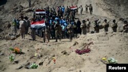 Tentara Irak berkumpul di kuburan massal tentara Syiah dari Kamp Speicher yang tewas akibat militan ISIS di kompleks mantan presiden Irak Saddam Hussein di Tikrit, 6 April 2015.
