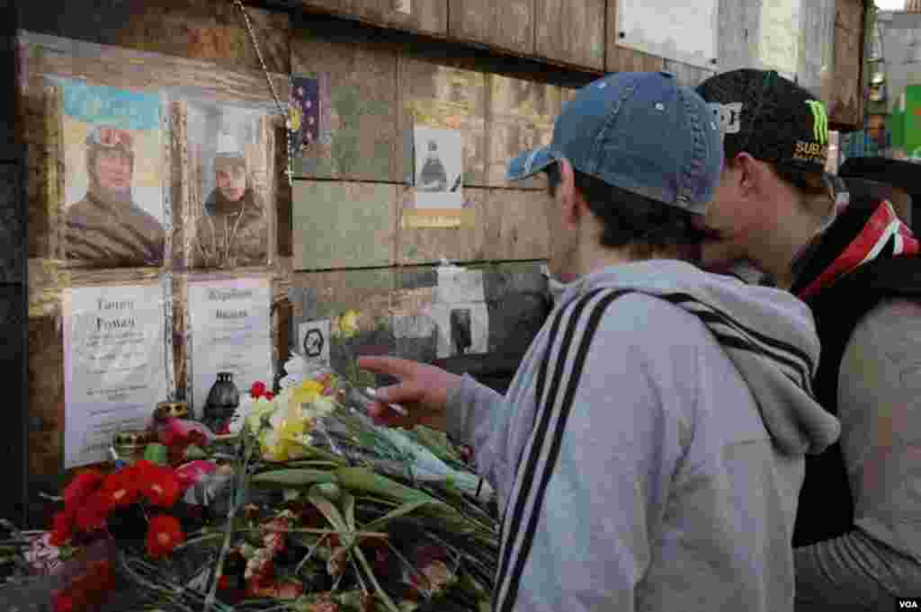 Visitors to Maidan look at a makeshift memorial for two of the more than 100 people killed in anti-government protests earlier this year. (Steve Herman/VOA)