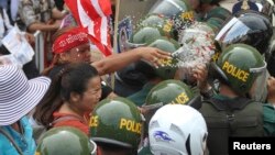 ស្ត្រី​ម្នាក់​នៃ​តំបន់​បឹងកក់ បាន​​បាច​​​អំបិល​និង​ម្ទេស​ទៅ​លើ​ប៉ូលិស ដែល​បាំង​ផ្លូវ ក្នុង​ពេល​ធ្វើ​បាតុកម្ម​មួយ​ នៅ​ក្នុង​ទីក្រុង​ភ្នំពេញ​នៃ​ប្រទេស​កម្ពុជា នៅ​ខែមិថុនា ឆ្នាំ២០១៣។