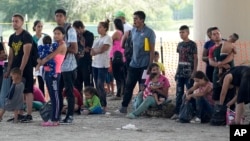 Para migran Amerika Tengah yang menyeberang ke AS dari Meksiko menunggu permohonan suaka mereka untuk diproses oleh agen Patroli Perbatasan AS, di Eagle Pass, Texas (foto: dok). 