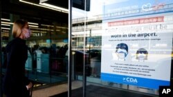 FILE - In this July 2, 2021 photo, a traveler walks in Terminal 3 as a sign stating face coverings are required is displayed at O'Hare International Airport in Chicago. 
