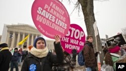 Abortion rights protesters hold signs as anti-abortion activists march past the Capitol to the Supreme Court in Washington, Jan. 25, 2013.