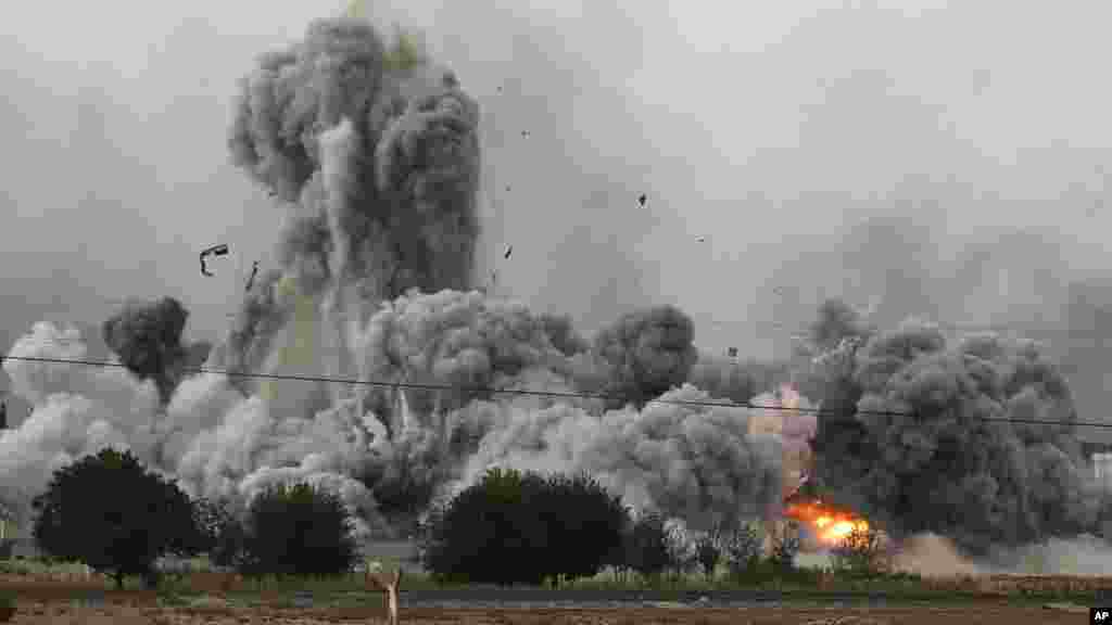 Thick smoke, debris and fire rise following an airstrike by the U.S.-led coalition in Kobani, Syria as fighting intensified between Syrian Kurds and the militants of Islamic State group, as seen from Mursitpinar on the outskirts of Suruc, at the Turkey-Syria border, Sunday, Oct. 12, 2014.