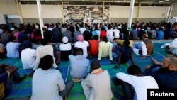 FILE - Migrants attend prayers at a detention center in Tripoli, Libya, June 15, 2018.