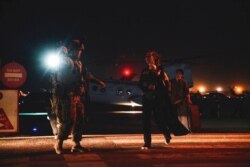 រូប​ឯកសារ៖ ទាហាន​ម៉ារីន​អាមេរិក​ម្នាក់​ការពារ​សន្តិសុខបុគ្គលិក​ក្រសួង​ការបរទេស​អាមេរិក​មួយ​រូប​ដែល​ពរ​កូន ដើម្បី​ត្រៀម​ជម្លៀស​ចេញ​នៅ​អាកាសយានដ្ឋាន​អន្តរជាតិ Hamid Karzai នៃ​ក្រុង​កាប៊ុល ប្រទេស​អាហ្វហ្គានីស្ថាន​កាល​ពី​ថ្ងៃ​ទី​១៥ ខែ​សីហា ឆ្នាំ​២០២១។