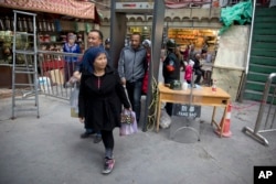 In this Nov. 4, 2017 photo, residents past through one of the many security check points in Kashgar in western China's Xinjiang region.(AP Photo/Ng Han Guan)