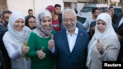 Rached Ghannouchi (C), leader of the Tunisian Islamist party Ennahda, gestures with his wife and two daughters Yousra (L) and Soumaya (2nd L) at a polling station during an election in Tunisia October 26, 2014.Tunisians voted on Sunday in parliamentary el