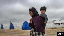 Seorang lansia Suriah menggendong anak di Kamp Washukanni dekat kota Kurdi, Hasakeh, di Suriah, 17 Februari 2020. 
