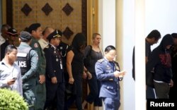 ជន​ភៀស​ខ្លួន​៣នាក់​ ក្នុង​ចំណោម​ជន​ភៀស​ខ្លួន​ទាំង​៤​ដែល​មក​ពី​កោះ​ណូរូ​ (បុរស​ពាក់​មួក​នៅ​ខាង​ឆ្វេង ស្រ្តី​ក្នុង​សំលៀក​បំពាក់​អាវ​មាន​មួក​គ្រប​ក្បាល​ពណ៌​ខ្មៅ​នៅ​កណ្តាល​ និង​បុរស​ក្នុង​សំលៀក​បំពាក់​អាវ​មាន​មួក​គ្រប​ក្បាល​ពណ៌​ខ្មៅ​នៅ​ខាង​មុខ​ត្រូវ​បាន​អម​ដោយ​ប៉ូលីស​កម្ពុជា​ ខណៈ​ពេល​ដែល​ពួក​គេ​បាន​មក​ដល់​ព្រលាន​យន្តហោះ​អន្តរជាតិ​ភ្នំពេញ​ កាល​ពី​ថ្ងៃ​ទី​៤​ ខែ​មិថុនា​ ឆ្នាំ​២០១៥។