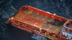 Migrants sit on the deck of the Italian supply vessel Asso Ventinove after they were rescued from an unseaworthy boat drifting in the Mediterranean Sea near the Bouri oilfields north of Libya, Oct. 2, 2021.