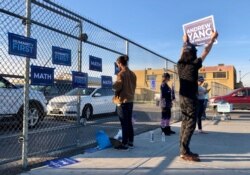 Macaulay Kong holds up a campaign sign in support of then-Democratic presidential candidate Andrew Yang, at a primary polling site. The "Yang Gang" continued to campaign for him even after he dropped out of the race. (Carolyn Presutti/VOA)