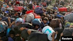 FILE - Migrant workers crowd up outside a bus station as they wait to board buses to return to their villages, in Ghaziabad, on the outskirts of New Delhi, March 28, 2020.