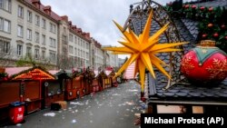 Seorang polisi, kanan, berdiri di Pasar Natal, tempat sebuah mobil menabrak kerumunan pada Jumat malam, di Magdeburg, Jerman, Sabtu, 21 Desember 2024. (Michael Probst/AP)