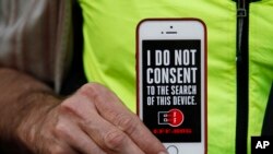 In this file photo, a man holds up his iPhone during a rally in support of data privacy outside the Apple Store in San Francisco, Feb. 23, 2016.