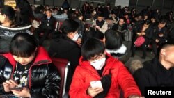 Para penumpang kereta api di Stasiun Kereta Api Beijing Barat mengenakan topeng, 20 Januari 2020.