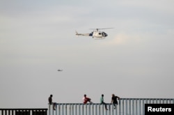 Migrants, part of a caravan of thousands trying to reach the U.S., sit on top of the border fence between Mexico and the United States, after arriving in Tijuana, Mexico, Nov. 13, 2018.