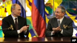 Russia's President Vladimir Putin, left, and Cuba's President Raul Castro applaud at Revolution Palace in Havana, Cuba, July 11, 2014.