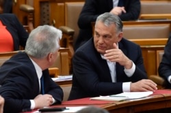 Hungarian Prime Minister Viktor Orban, right, chats with his deputy Zsolt Semjen during a plenary session of the Parliament in Budapest, Hungary, Budapest, Hungary, Monday, March 30, 2020. (Zoltan Mathe/MTI via AP)