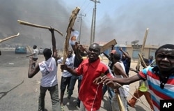 People holding wooden and metal sticks demonstrate in Nigeria's northern city of Kano where running battles broke out between protesters and soldiers on Monday.