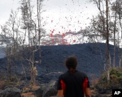 Abe Pedro watches lava shoot from a fissure on Pohoiki Road, May 18, 2018, near Pahoa, Hawaii.