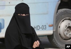 FILE - A Saudi woman waits outside a polling center as she prepares to cast her ballot during the country's municipal elections in Riyadh, Saudi Arabia, Dec. 12, 2015. A study at that time by Human Rights Watch said Saudi Arabia’s male guardianship system was the most significant impediment to realizing women’s rights in the kingdom.