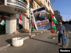 A man looks at a poster depicting Palestinian President Mahmoud Abbas and Prime Minister Rami Hamdallah in Gaza City, Oct. 1, 2017.