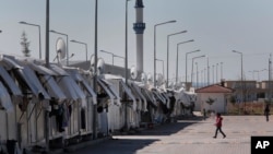Refugees walk at the Oncupinar refugee camp for Syrian refugees next to the border crossing with Syria, near the town of Kilis in southeastern Turkey, Thursday, March 17, 2016.