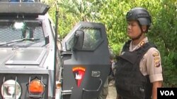 Kapolres Poso AKBP Susnadi berdiri di sisi kendaraan yang terkena tembakan. (VOA/Yoanes Litha)