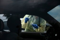 Physician assistant Nicole Kramer prepares to collect a nasal swab sample from a patient for COVID-19 testing at Xpress Urgent Care, June 25, 2020, in Tustin, Calif.