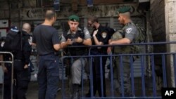 Polisi Israel memeriksa dokumen seorang pria yang berusaha memasuki kota tua Yerusalem hari Minggu (4/10). Israel mencabut peraturan keamanan ketat hari Selasa 6/10.