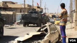 Seorang remaja memperhatikan pasukan Irak melewati daerah yang baru saja direbut dari kekuasaan ISIS di Mosul, Kamis (1/6).