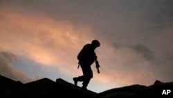 FILE - A U.S. soldier monitors a combat outpost in Afghanistan, Sept. 18, 2009. An effort to track extremism within the U.S. military is facing roadblocks, according to a new report.