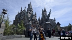 Guests pose before they enter Hogwarts School during a soft opening and media tour of "The Wizarding World of Harry Potter" theme park at the Universal Studios Hollywood in Los Angeles, California March 22, 2016. 