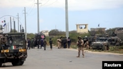 Tentara Italia dan Somalia dekat kendaraan baja di lokasi penyerangan konvoi militer Italia, di Mogadishu, Somalia, 30 September 2019.