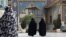 Head-to-toe veiled Iranian women walk at the shrine of Saint Saleh in northern Tehran, April 6, 2021.