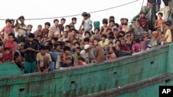 Para migran duduk di kapal mereka saat menunggu diselamatkan para nelayan di Aceh Timur (20/5). (AP/S. Yulinnas)