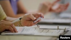 FILE - An election worker checks a voter's drivers license as North Carolina's controversial "Voter ID" law goes into effect for the state's presidential primary election at a polling place in Charlotte, North Carolina, March 15, 2016. 
