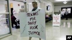 Kelly Jones, ex-wife of Infowars host Alex Jones, carries a sign as she arrives at the Travis County Courthouse, Aug. 1, 2018, in Austin, Texas. Alex Jones wants a Texas judge to dismiss a defamation lawsuit filed against him by families of some of the children killed in the 2012 mass shooting at Sandy Hook Elementary School.