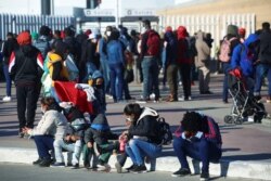 Migrants gather at the El Chaparral border crossing point to seek asylum in the U.S., in Tijuana, Mexico, Feb. 19, 2021.