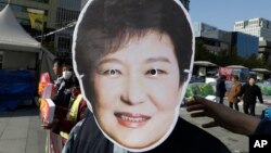 A South Korean protester wears a mask of South Korean President Park Geun-hye during a rally calling for Park to step down in downtown Seoul, South Korea, Nov. 11, 2016. Tens of thousands of South Koreans are expected to march in Seoul to demand Park's resignation on Saturday over a snowballing influence-peddling scandal involving Park's longtime confidante. 