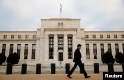 FILE - A man walks past the Federal Reserve Bank in Washington, D.C.